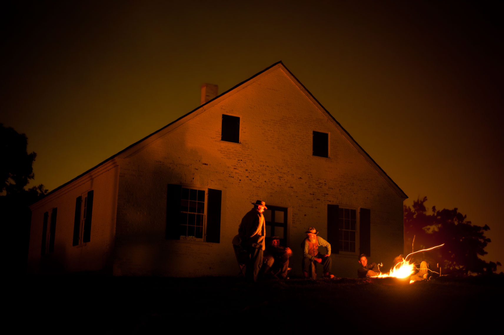 Civil War reenactors at Antietam: men sit around the campfire in front of historic Dunker Church on the battlefield