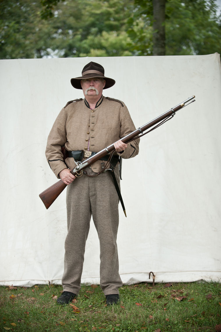 Civil War reenactors at Antietam: a reenactor stands with his musket in front of a tent