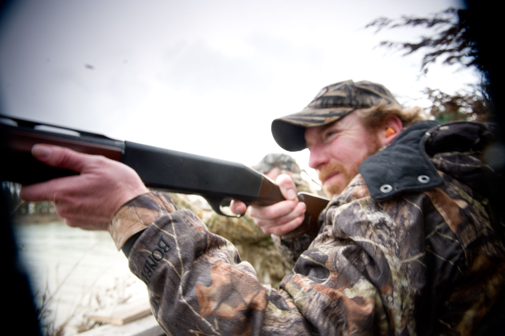 Hunting for waterfowl on the Eastern Shore of Maryland: hunter fires his shotgun at the approaching birds