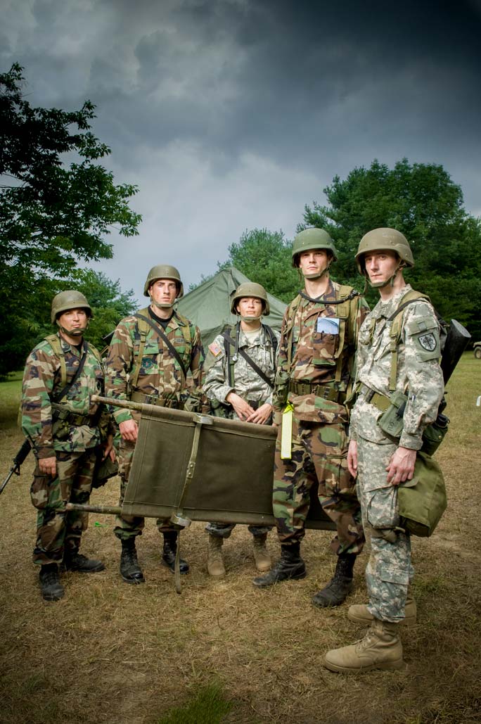 Army paramedics of the Uniformed Services University holding a stretcher and standing beneath a dramatic sky