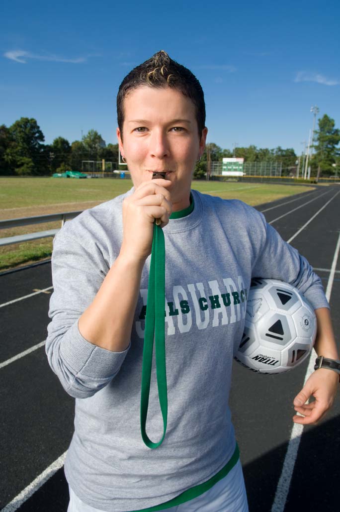 PE Teacher Heather Woodson holds a soccer ball and blows a whistle