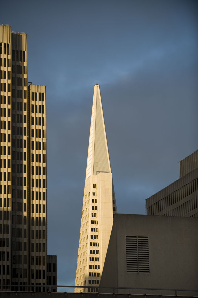 The top of the Transamerica Pyramid Building in the sunlight against a darkened sky in San Francisco, California