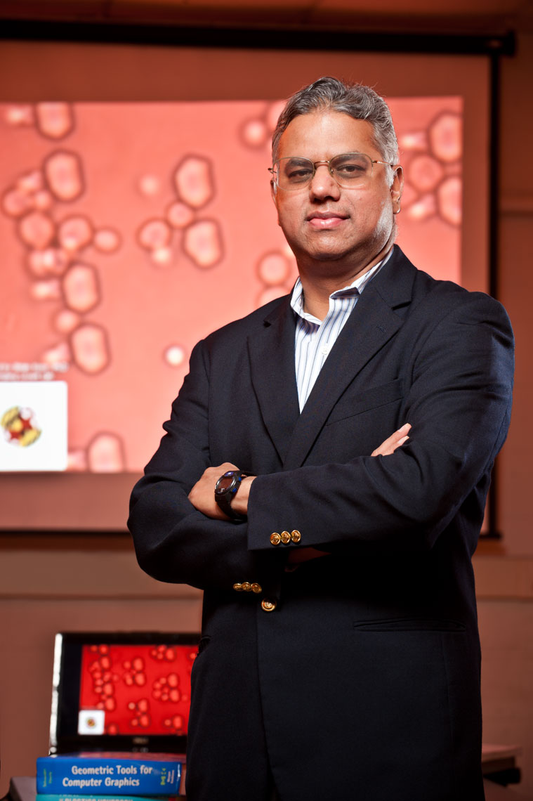 SK Gupta standing with his arms folded in front of a microscope projection