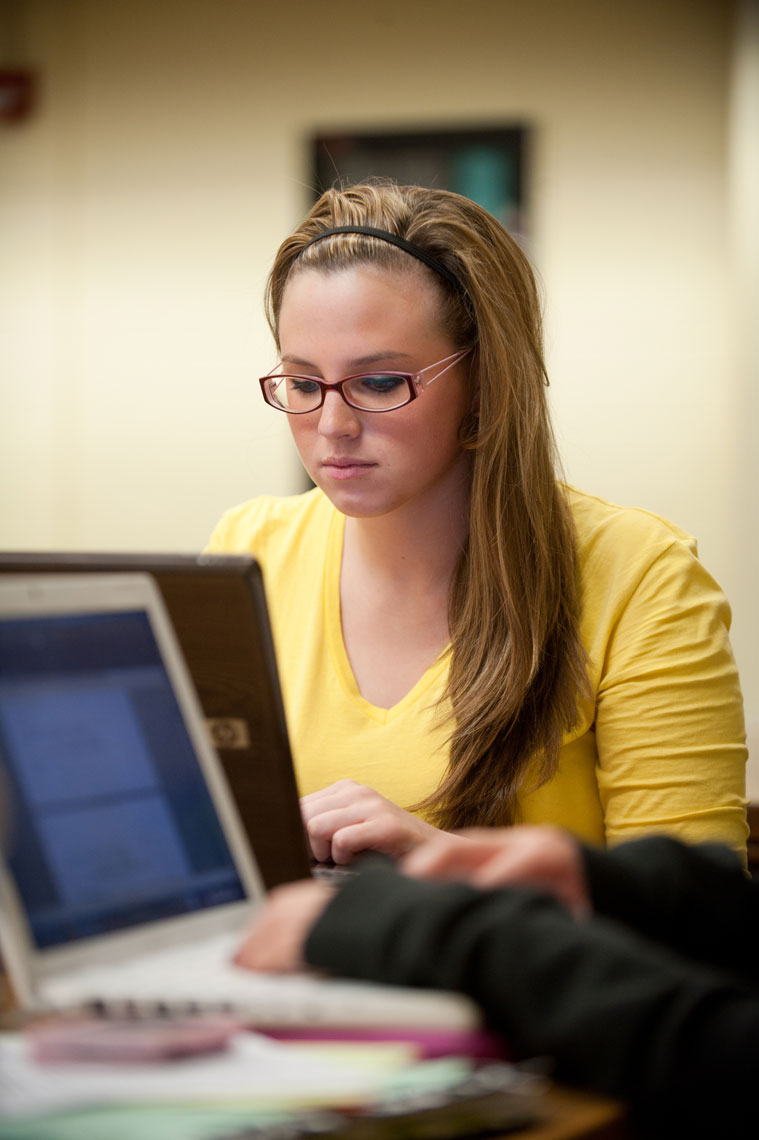 A student works at her laptop in a room at the library