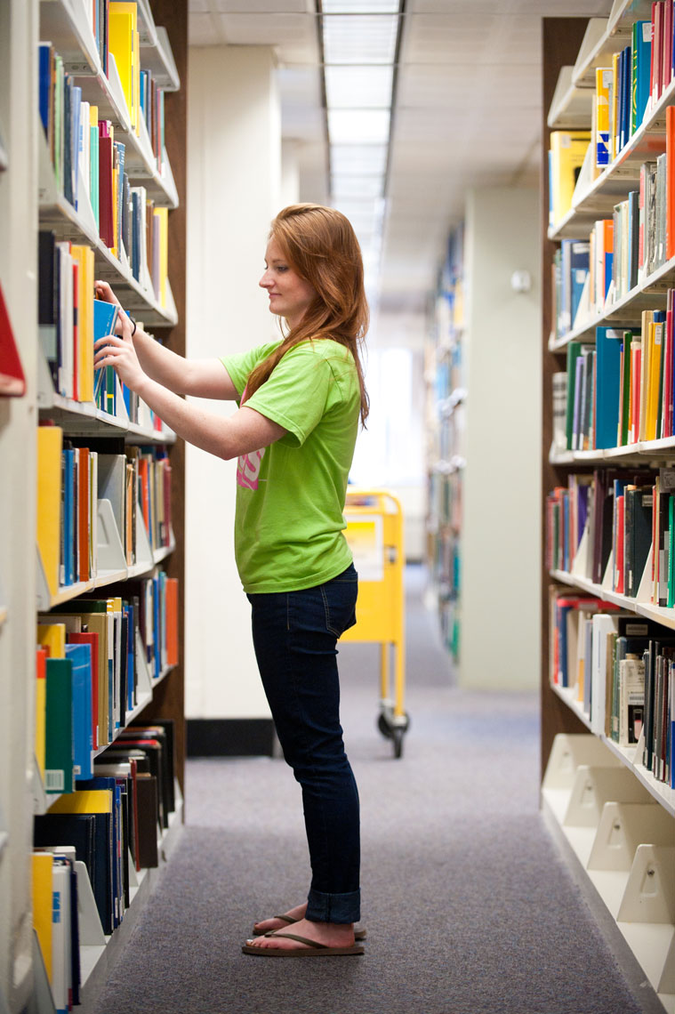 A student pulls a book from the stacks in the library