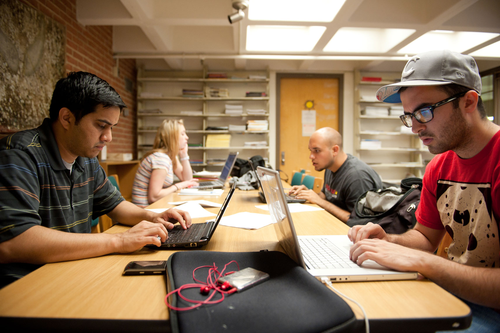 Students working at laptops at a table in the library