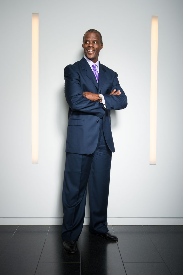 JC Watts smiling with his arms crossed in between two vertical lights