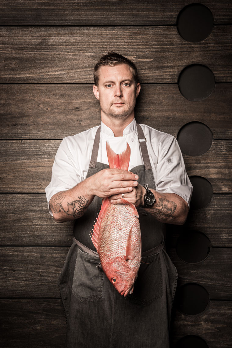 Bryan Voltaggio, Top Chef finalist, standing and holding a red snapper