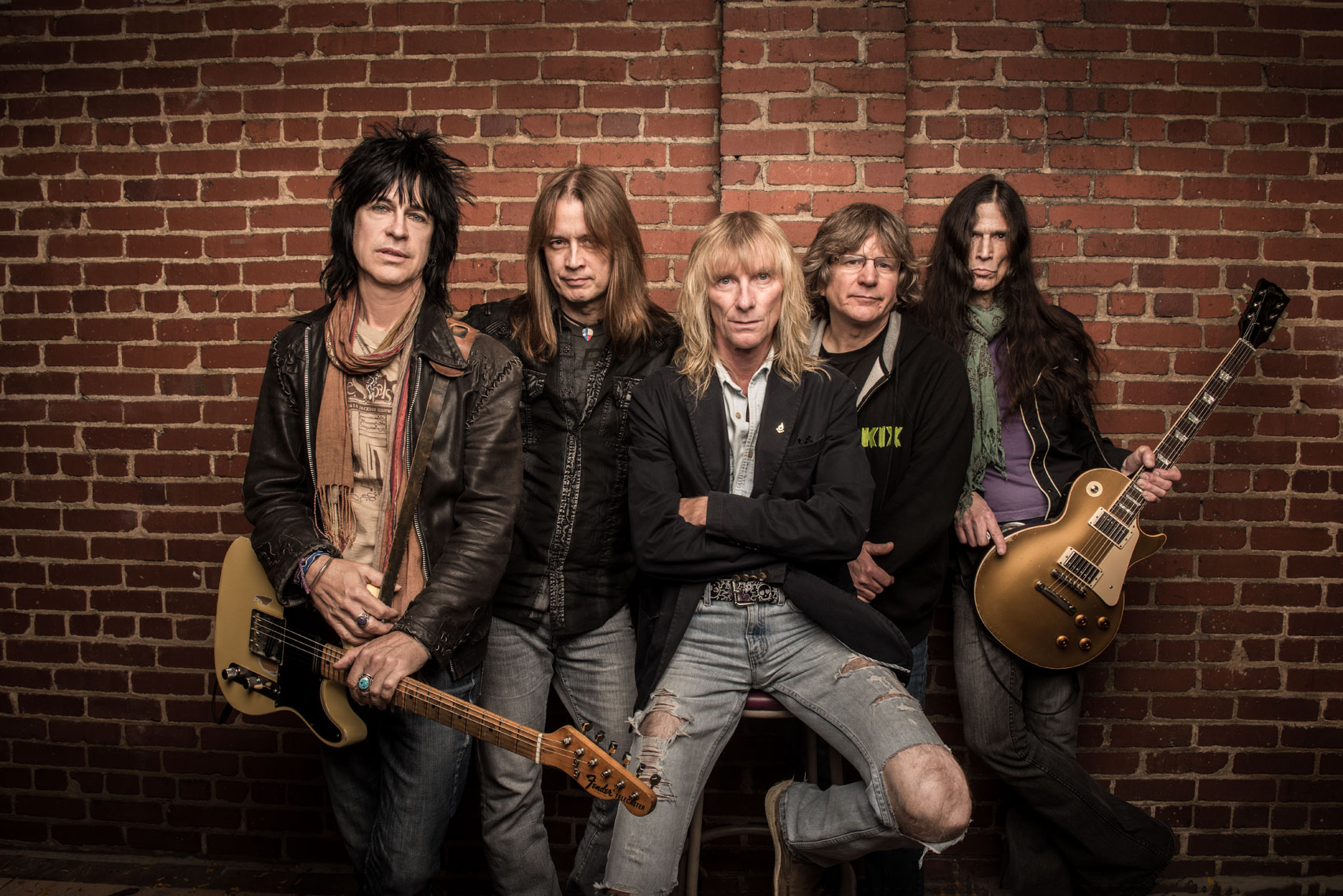 American rock band Kix standing together in front of a brick wall with guitars