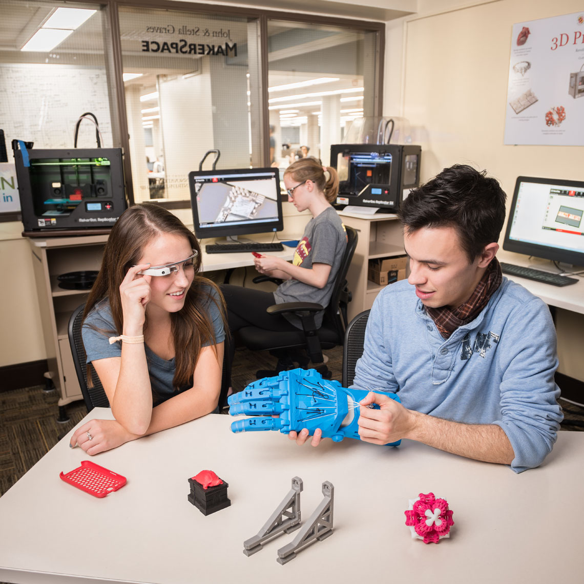 Students hold 3D printed items in a maker space lab