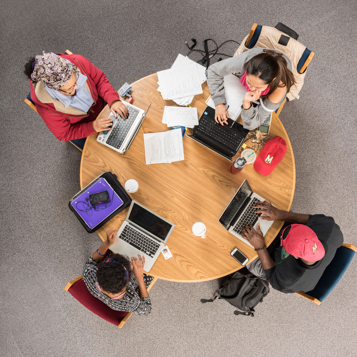 An overhead view of college students working at a round table in a library