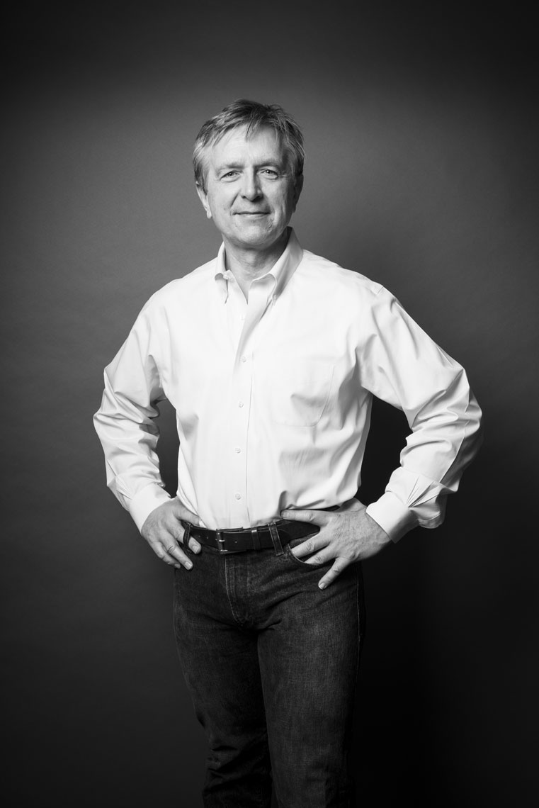 A black and white portrait of a man wearing a white shirt and jeans
