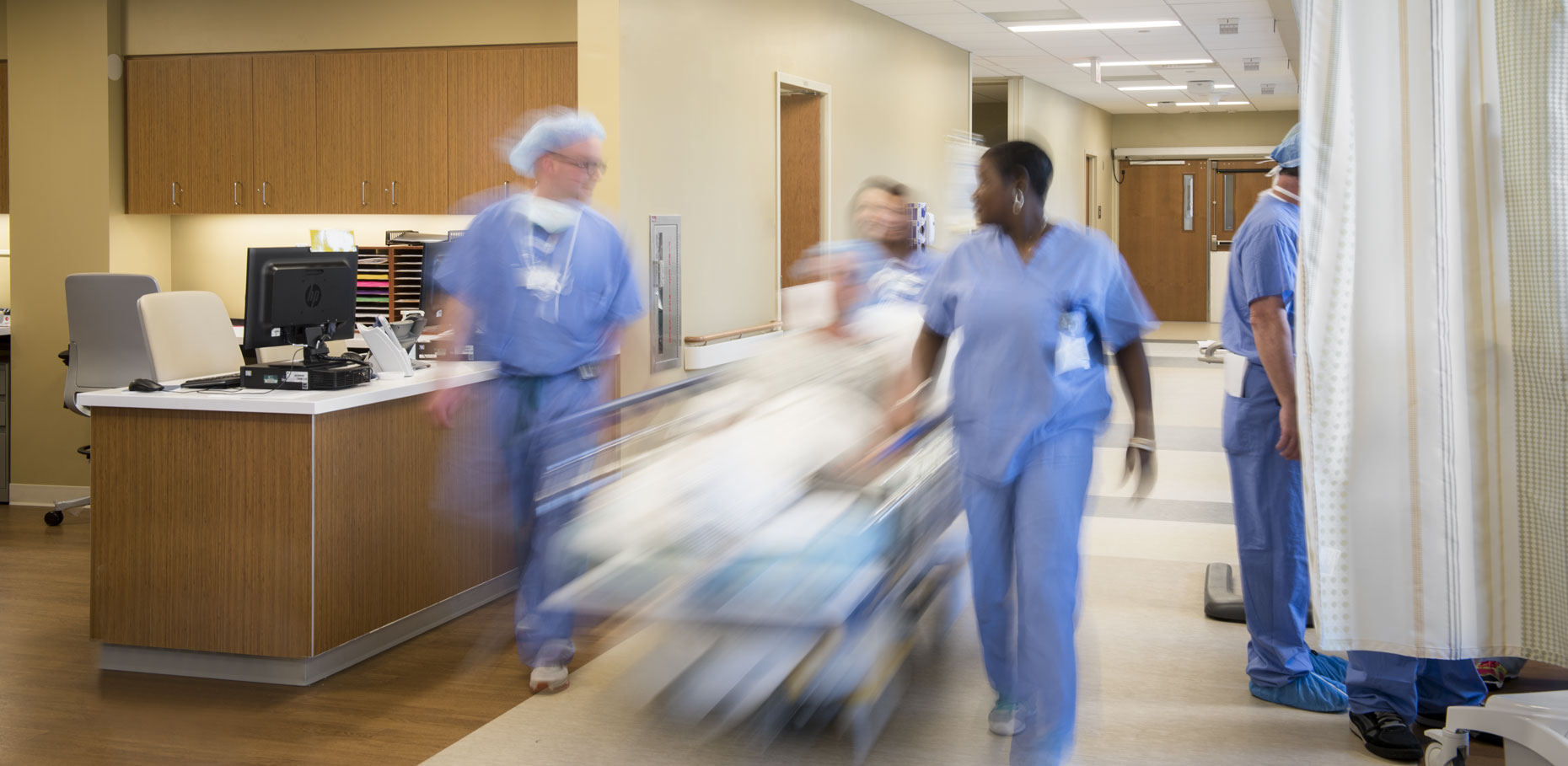 Nurses wheel a patient down a hallway at Holy Cross Hospital