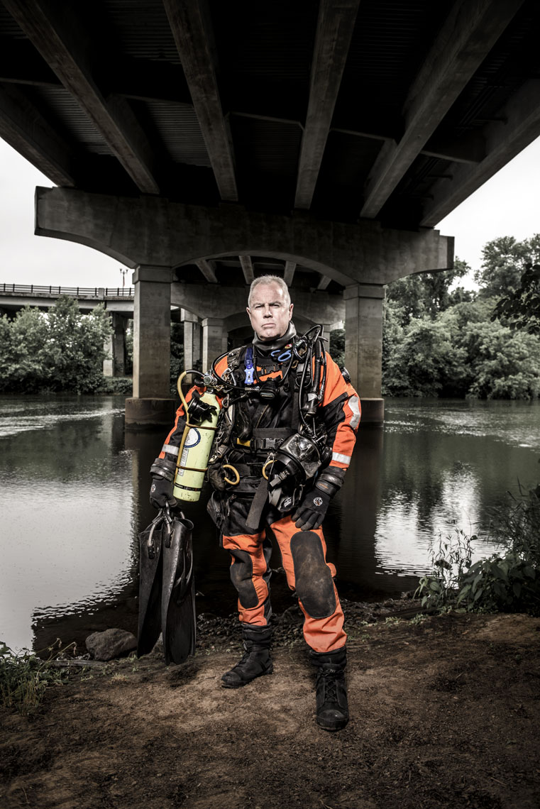 Mike Berry standing in front of water underneath a bridge in his scuba gear