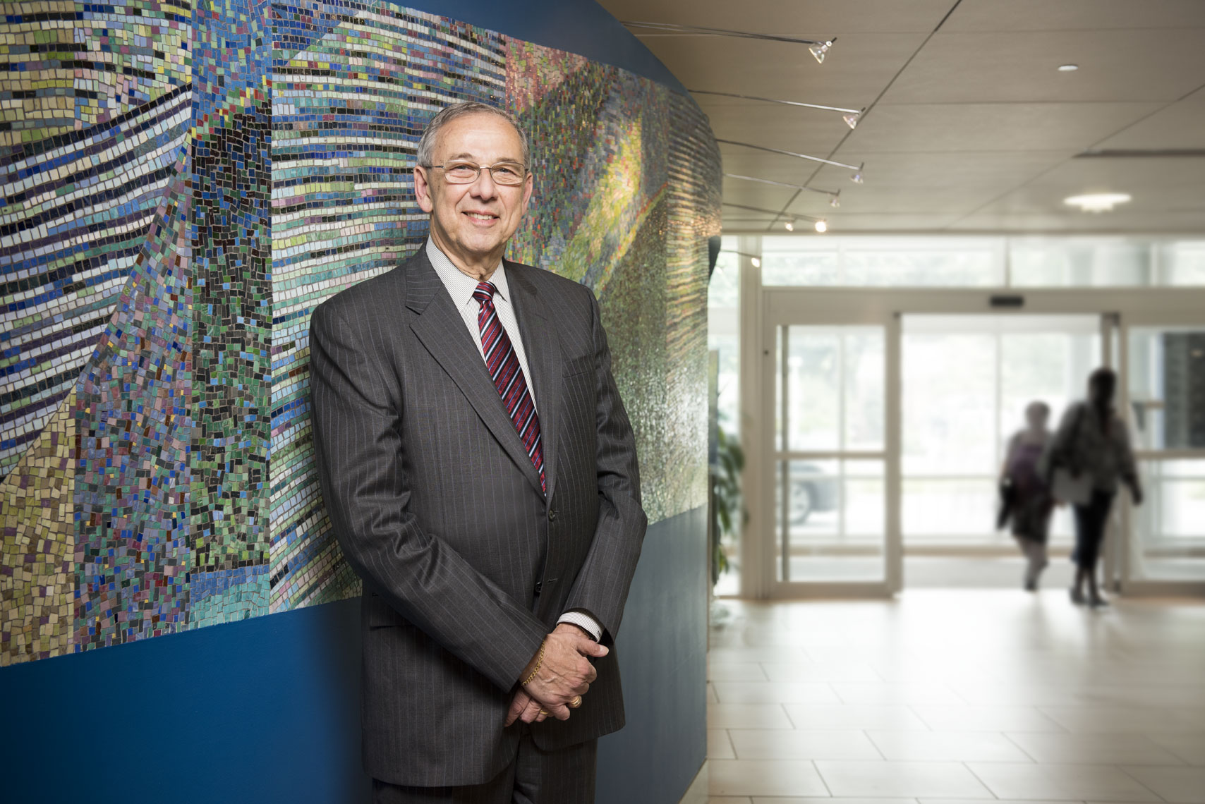 A smiling man in a suit standing against an art installation in a lobby
