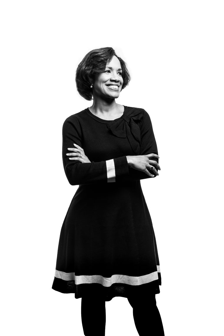 A black and white photo of a woman smiling against a white background