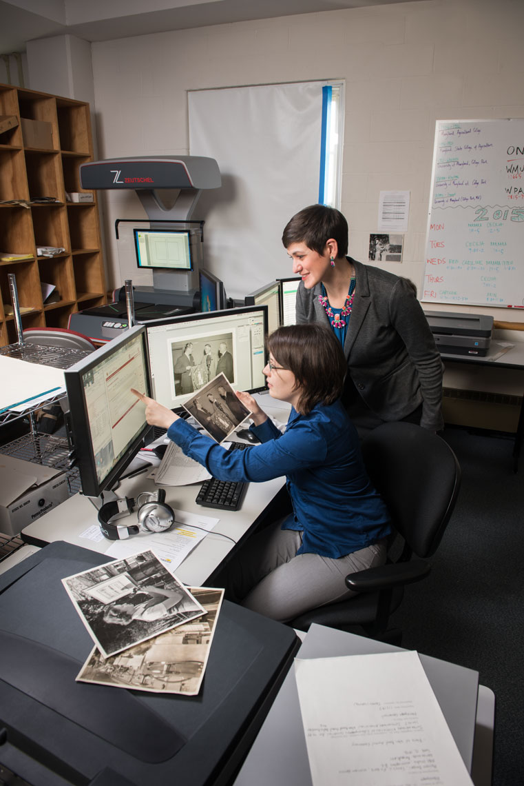 Two archivists digitize black and white photos at a computer
