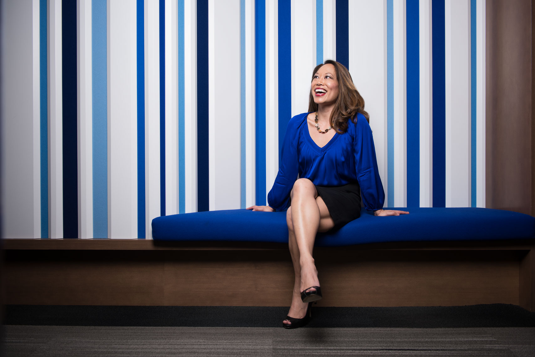 Ailsa Chang seated on a blue bench at NPR headquarters