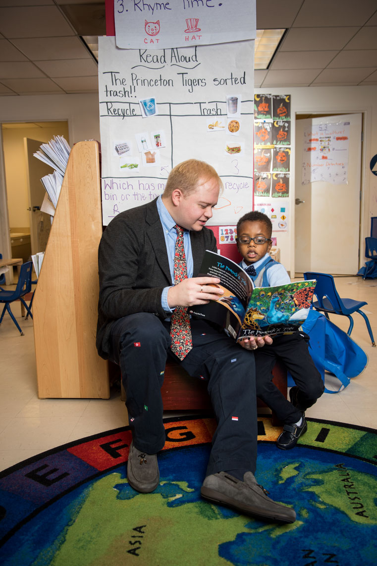 Principal Ryan Tauriainen reads a book to a child in a classroom