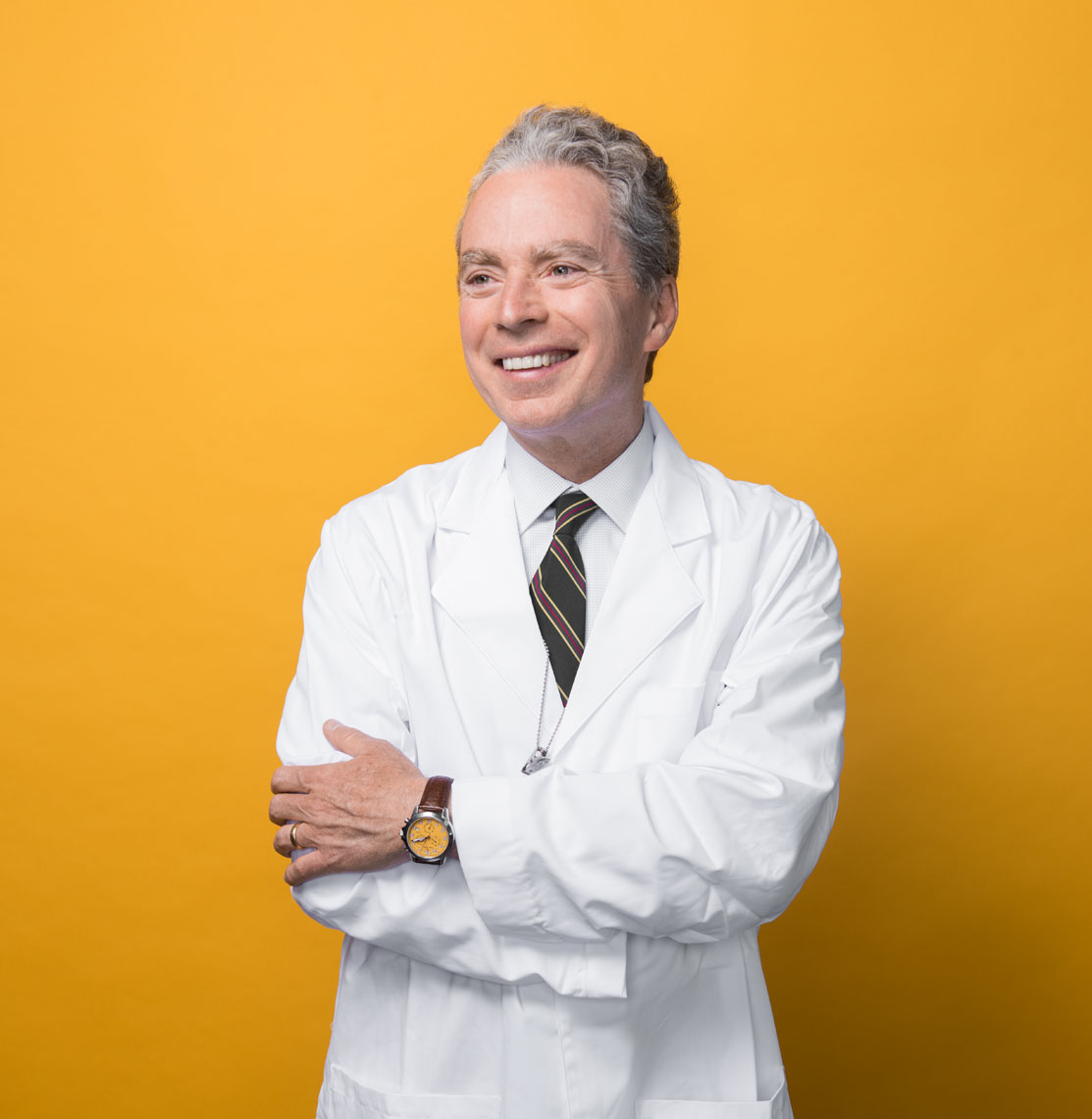 Dr. Paul Gurbel smiling in his lab coat in front of a yellow background