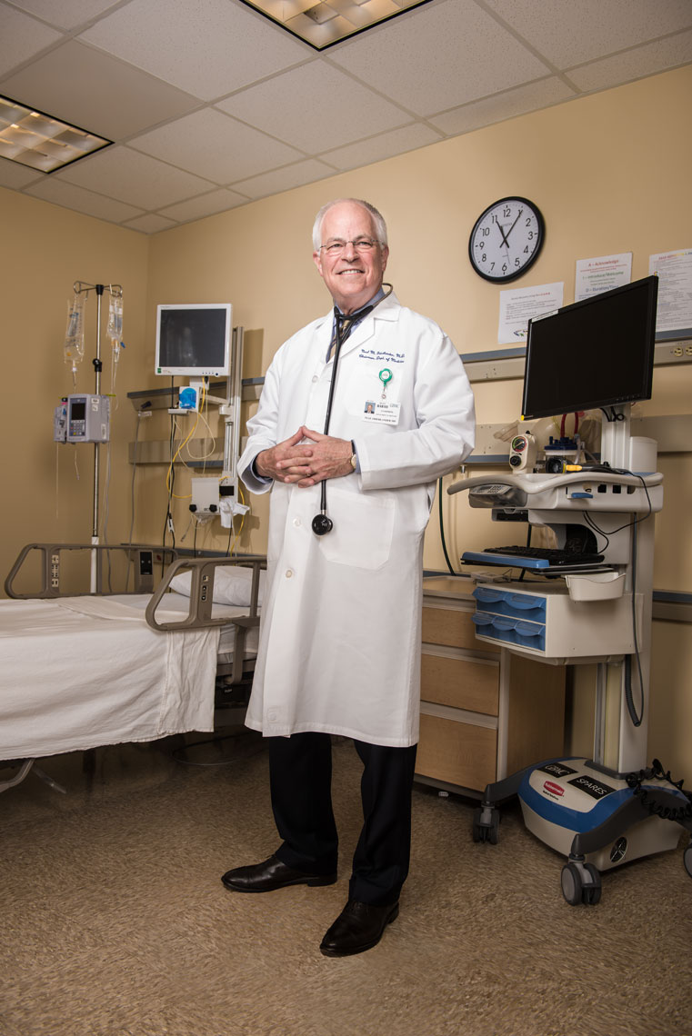 Dr. Neal Friedlander wearing a lab coat and stethoscope in a hospital exam room