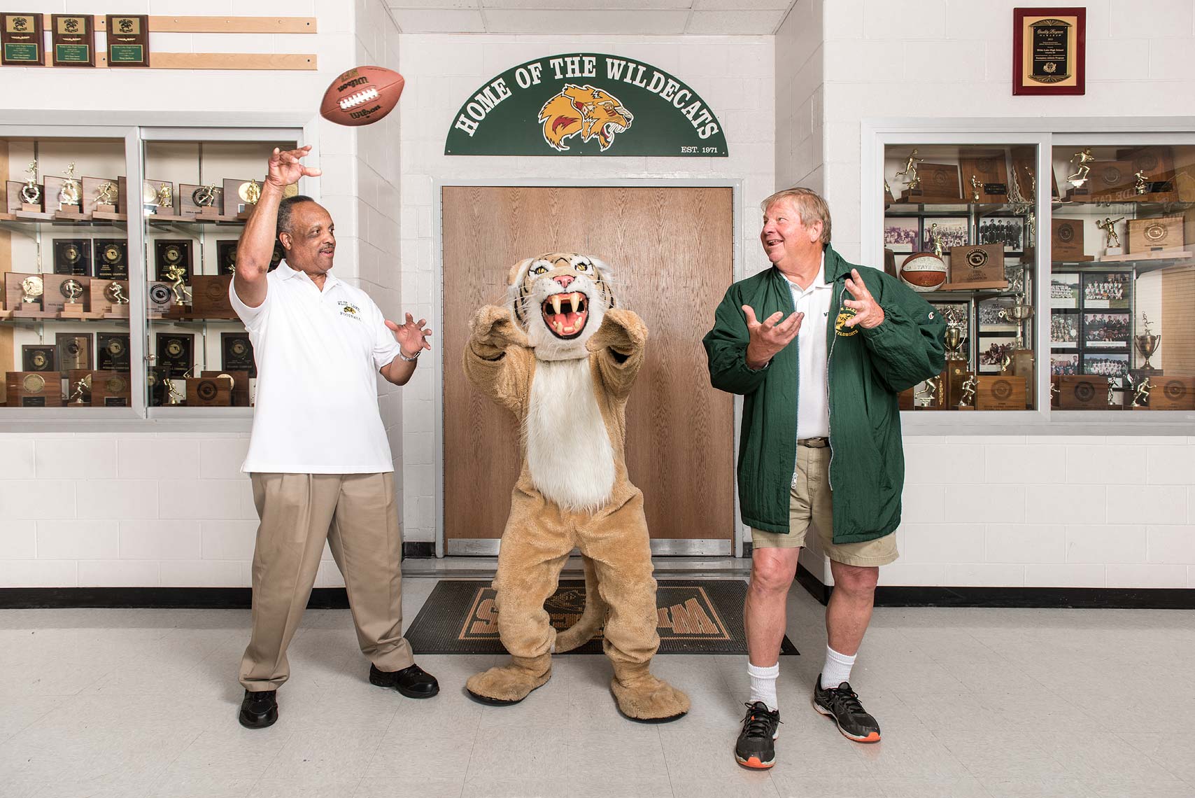 Two football coaches tossing a football with a tiger mascot
