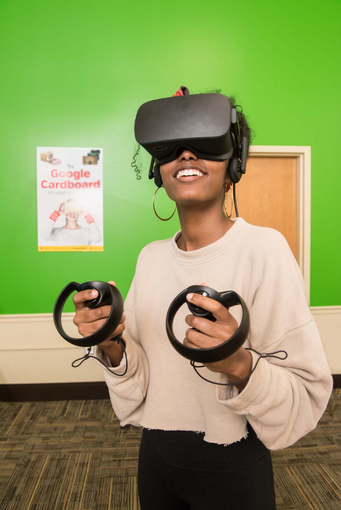 A student wears virtual reality headgear and smiles