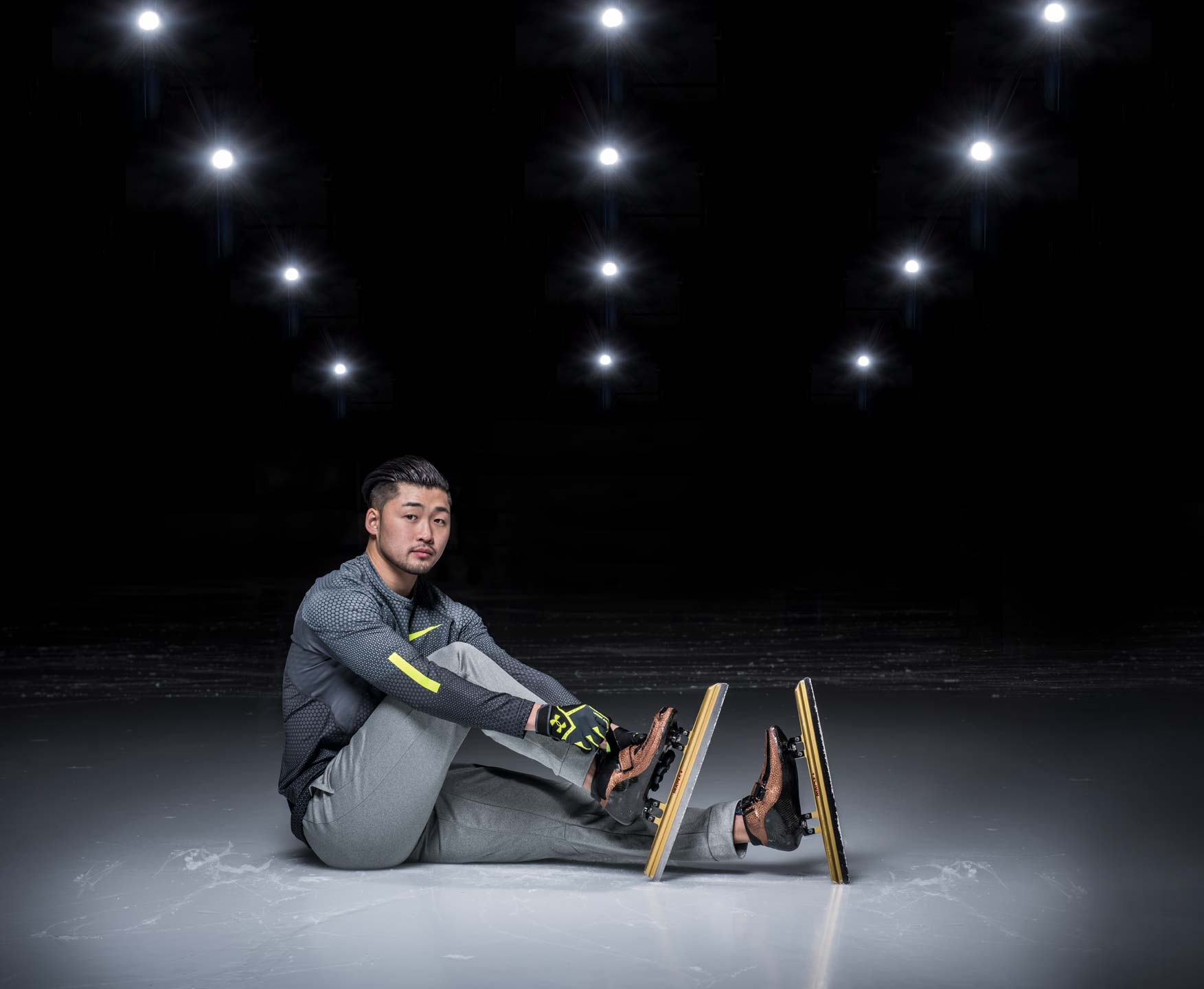 Speed skater Simon Cho adjusting his skates while seated on the ice