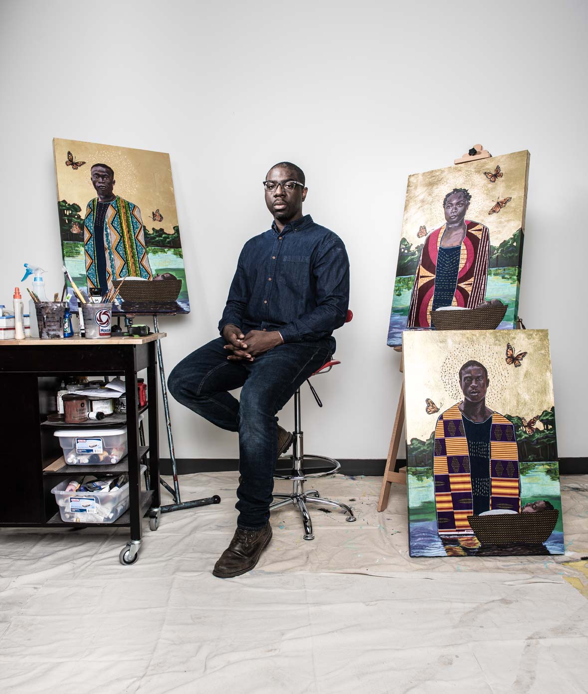 Artist Stephen Towns seated in front of his paintings in his Baltimore studio