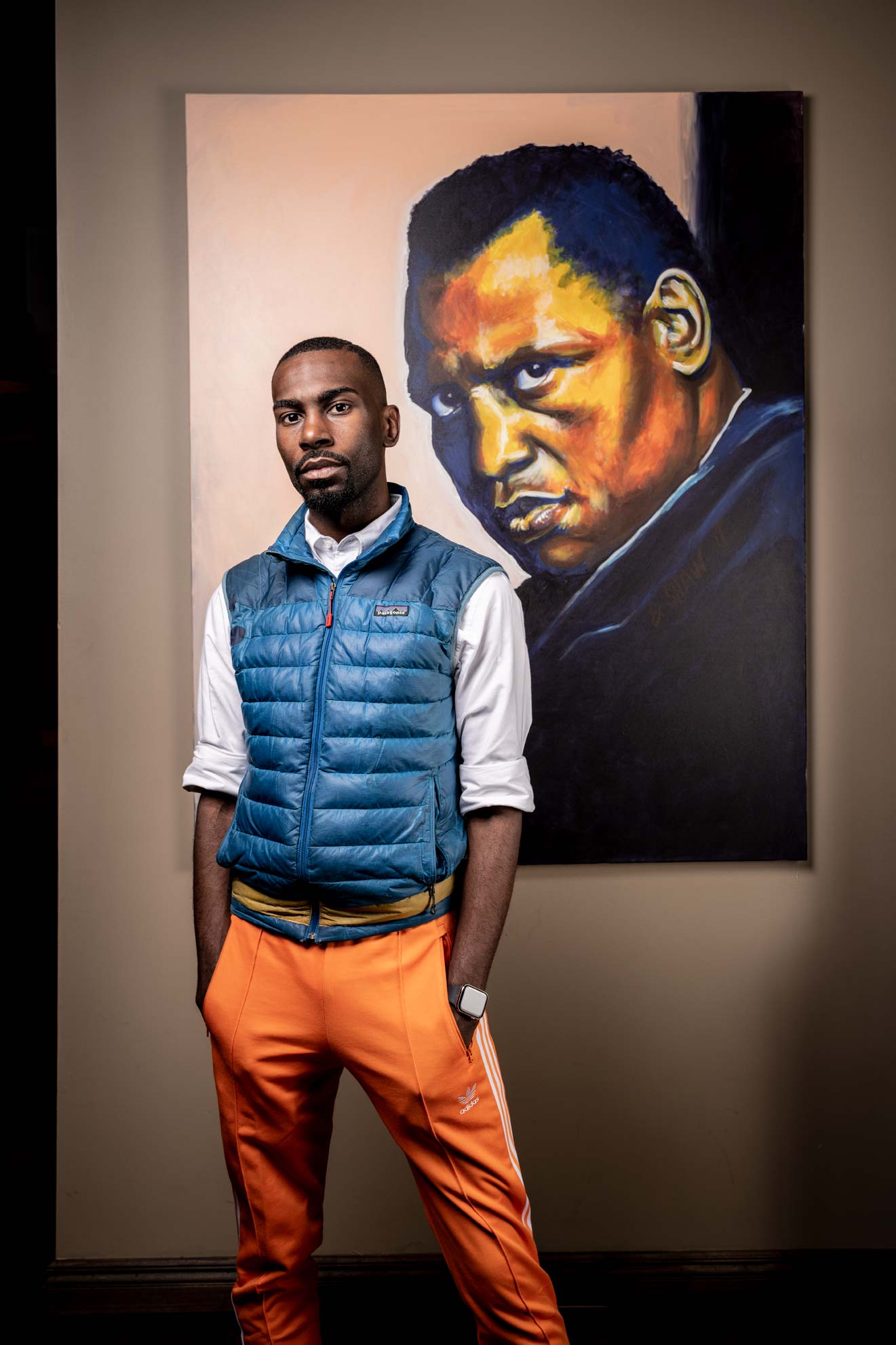 Social activistDeRay Mckesson wearing his signature blue vest in front of a painting of Paul Robeson