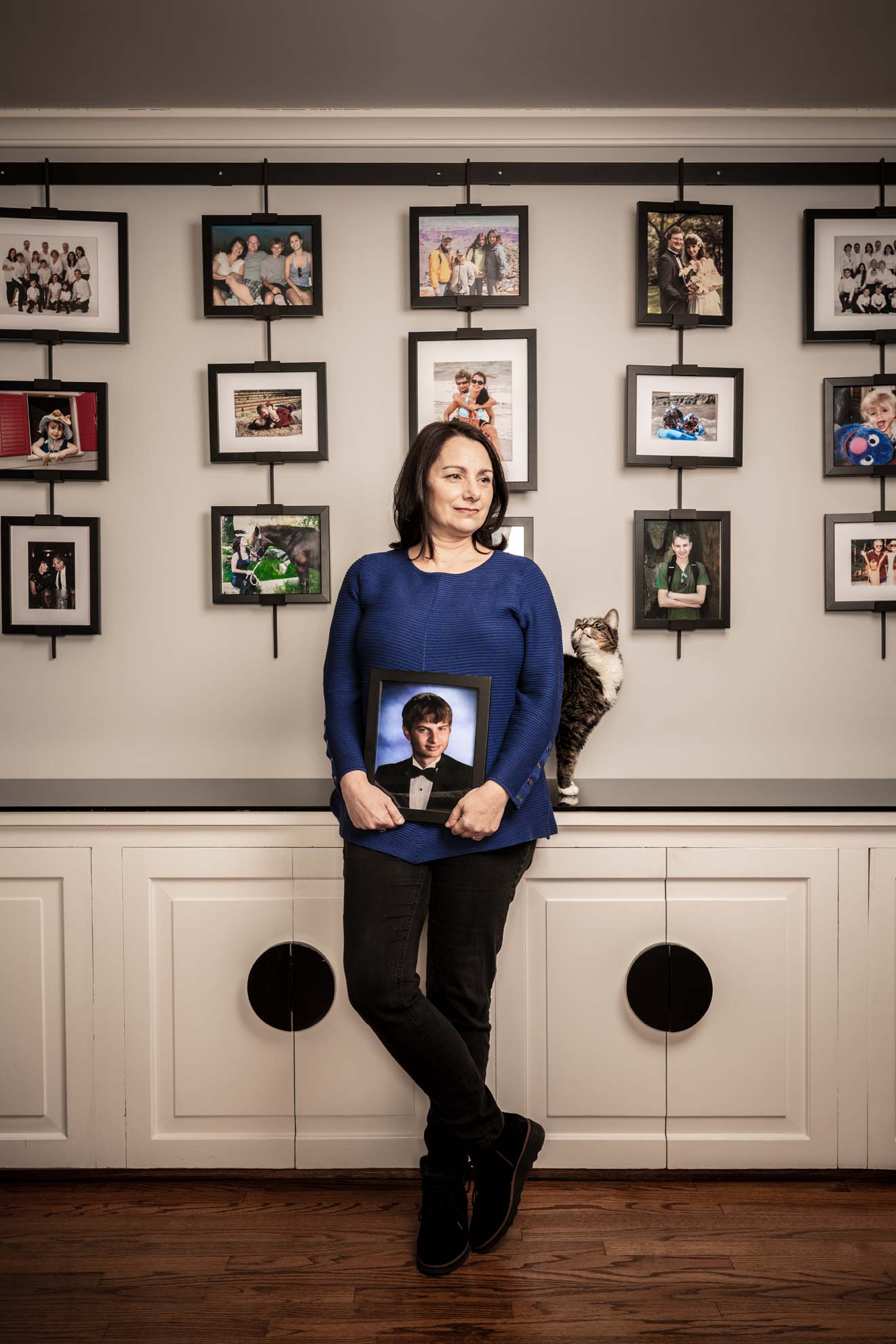 Caryn Anthony holding a portrait of her late son in front of a wall of family pictures