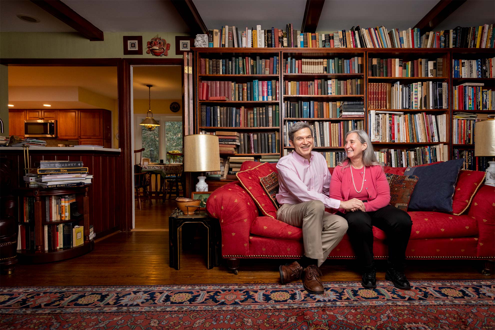 A couple smiling and laughing on a sofa in front of bookshelves