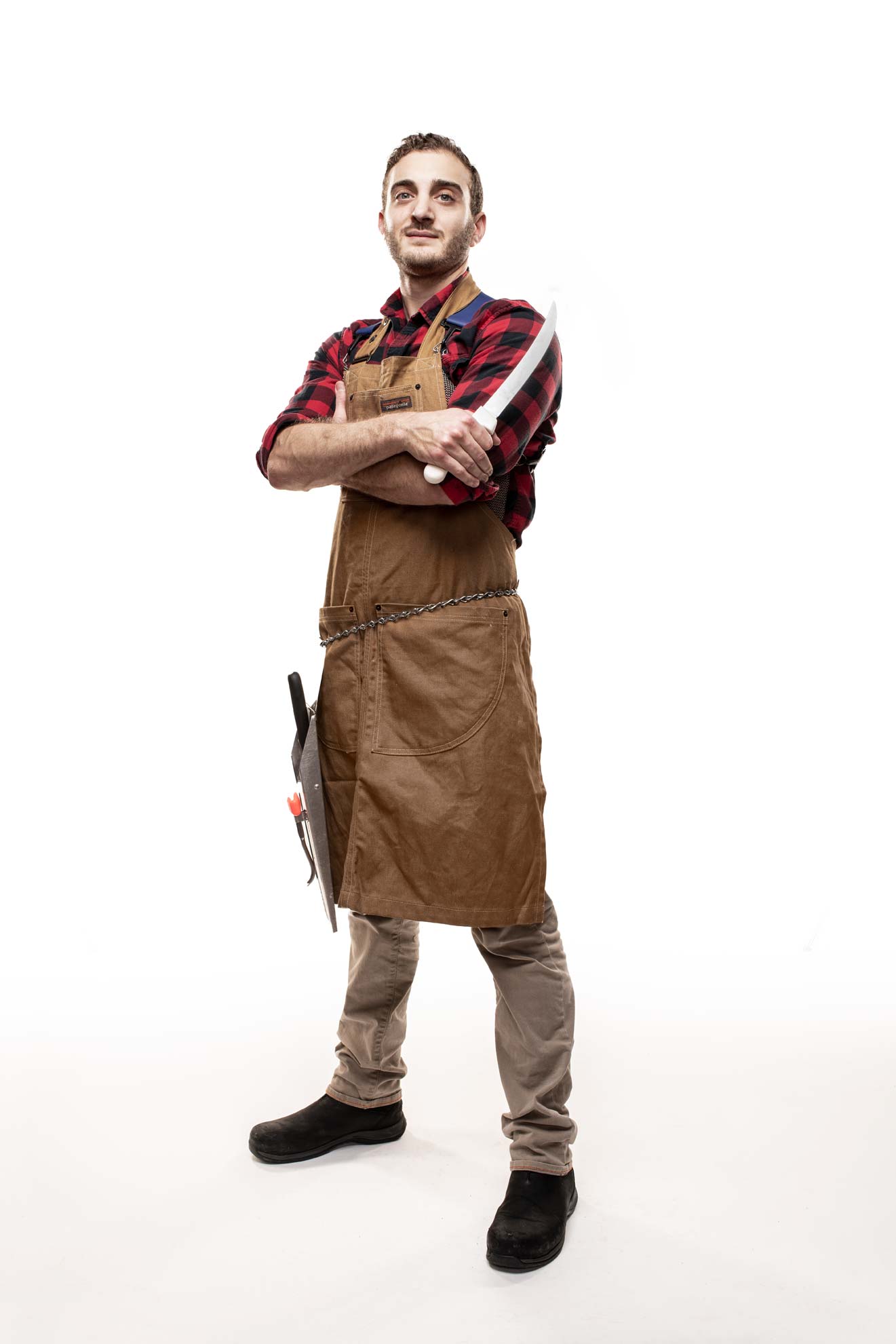 Butcher Mark Mancuso standing with his arms folded and holding a knife on a white background
