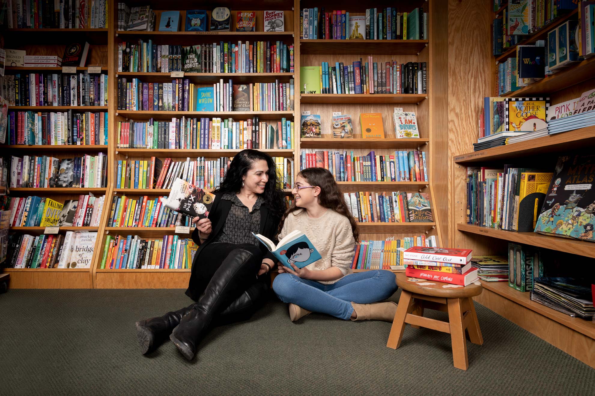 A mother and daughter reading books together on the floor of a bookstore