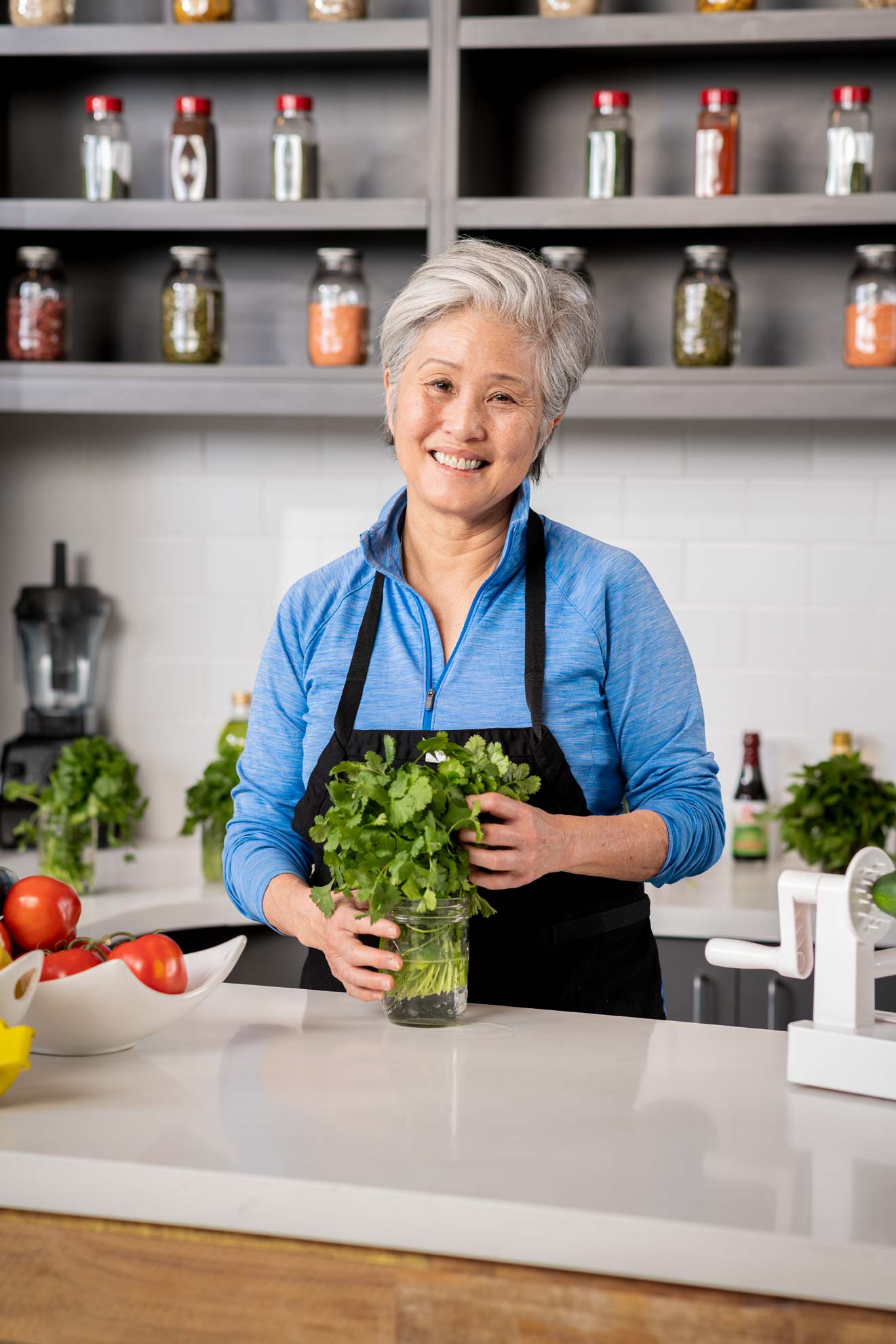 A woman smiling at a kitchen counter smiling with herbs