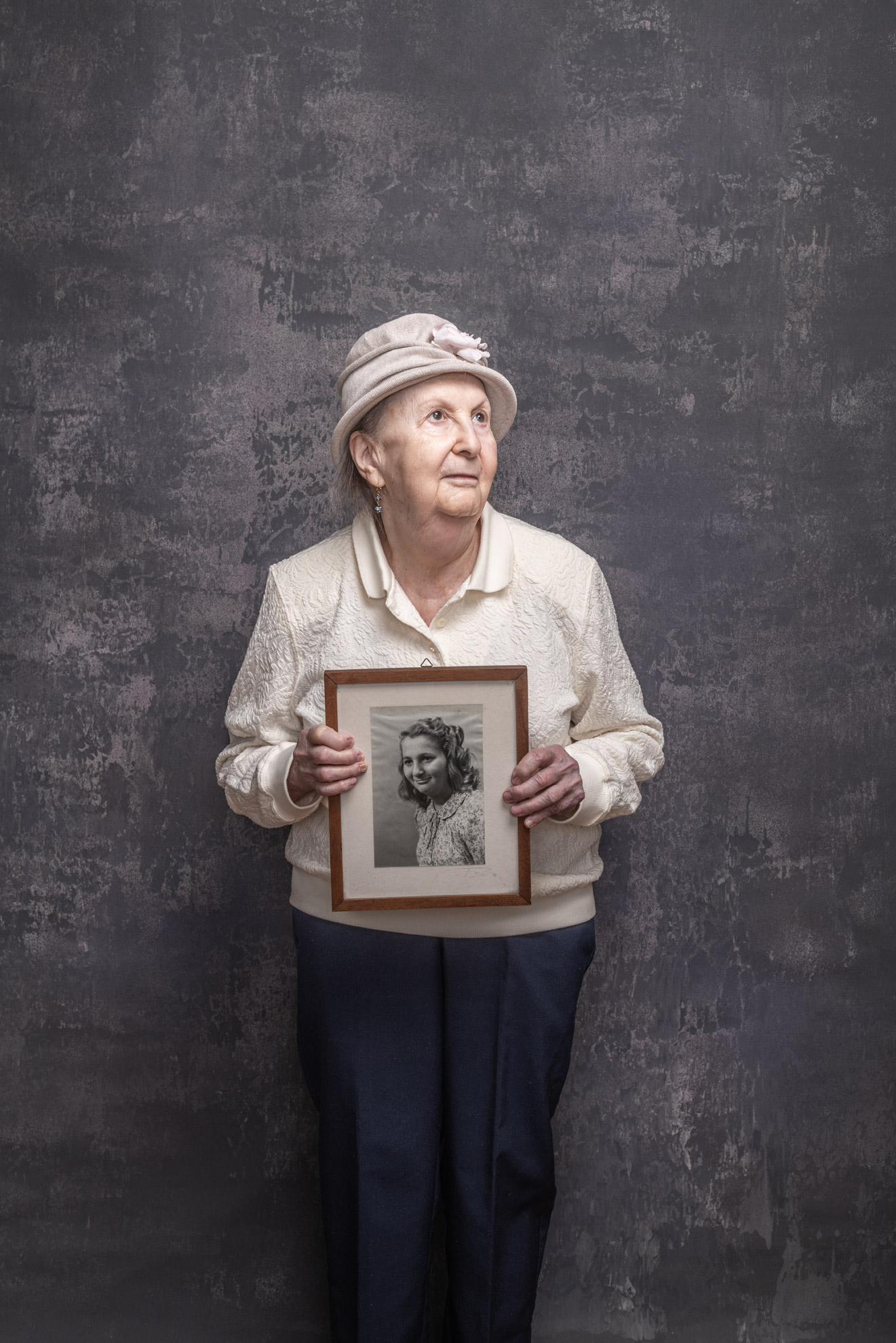 Holocaust survivor Goldie Kalib holding a portrait of herself as a young girl