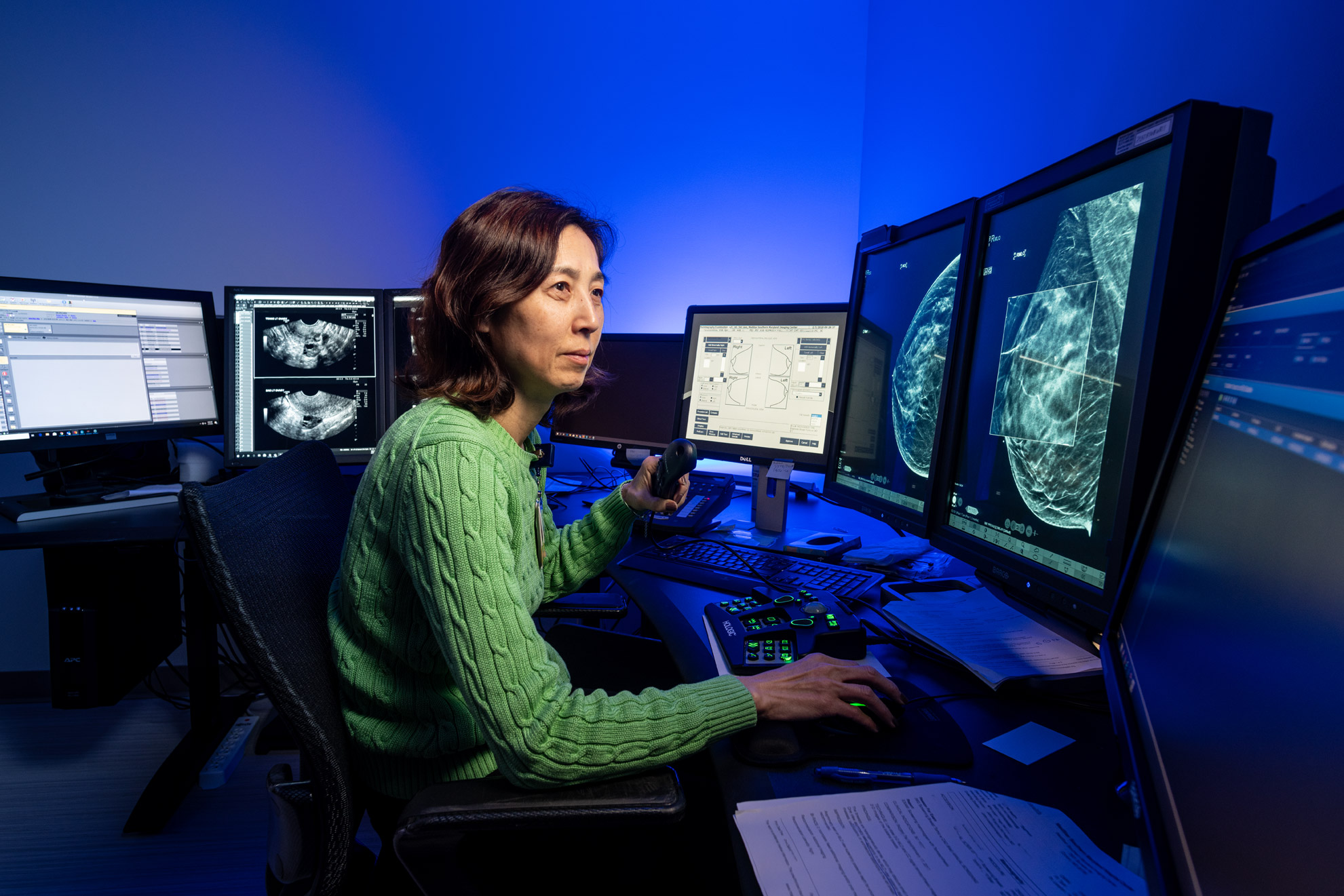 A doctor looks at mammograms on a computer screen with a blue background