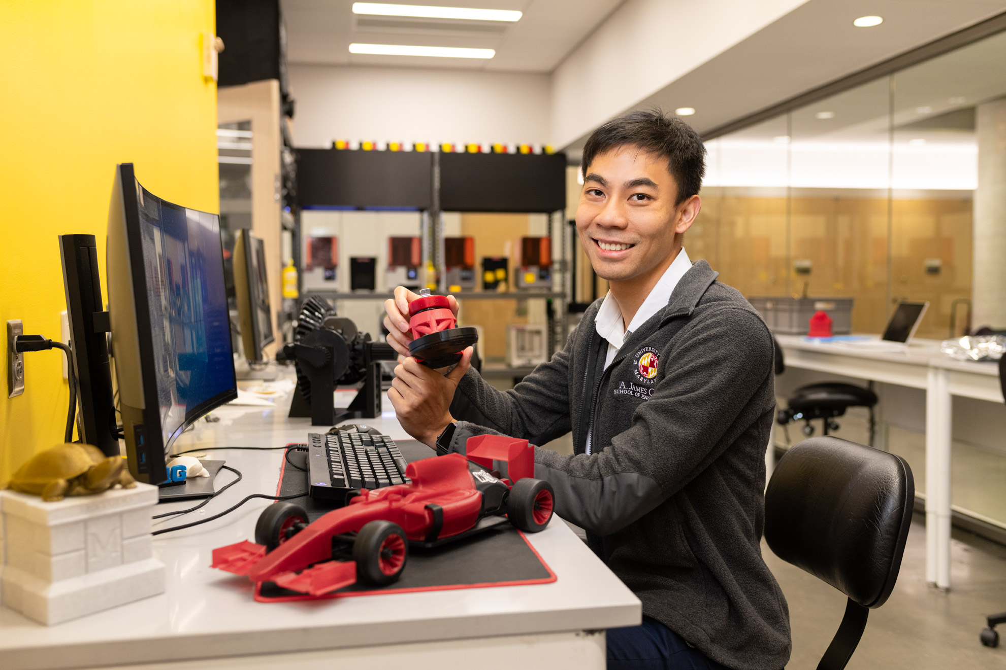 An engineering student holds 3-D printed models in a lab