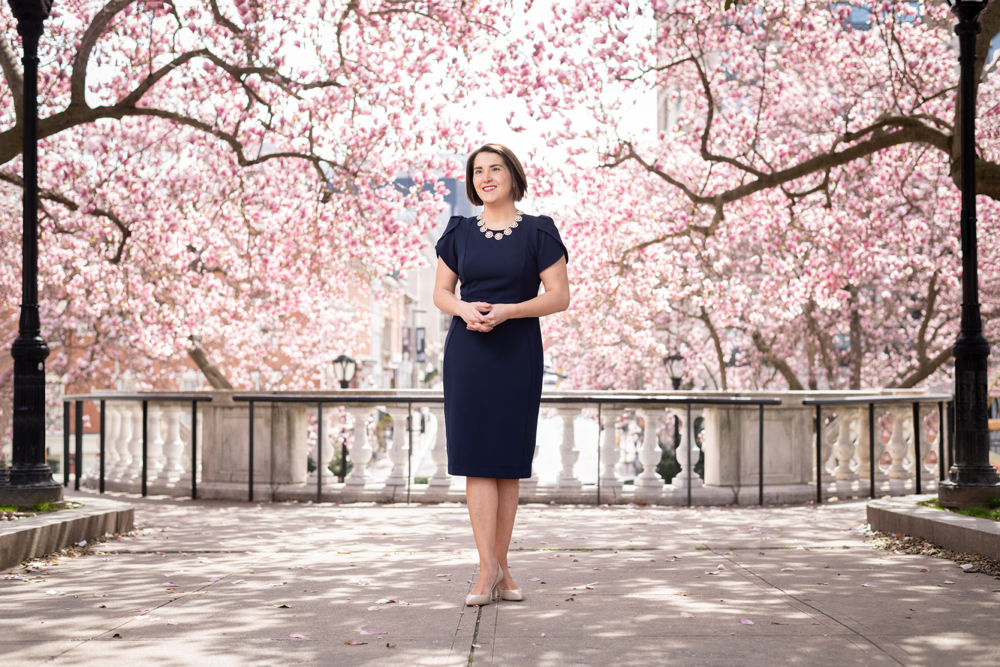 Soprano Chelsea Buyalos standing in front of pink flowering trees