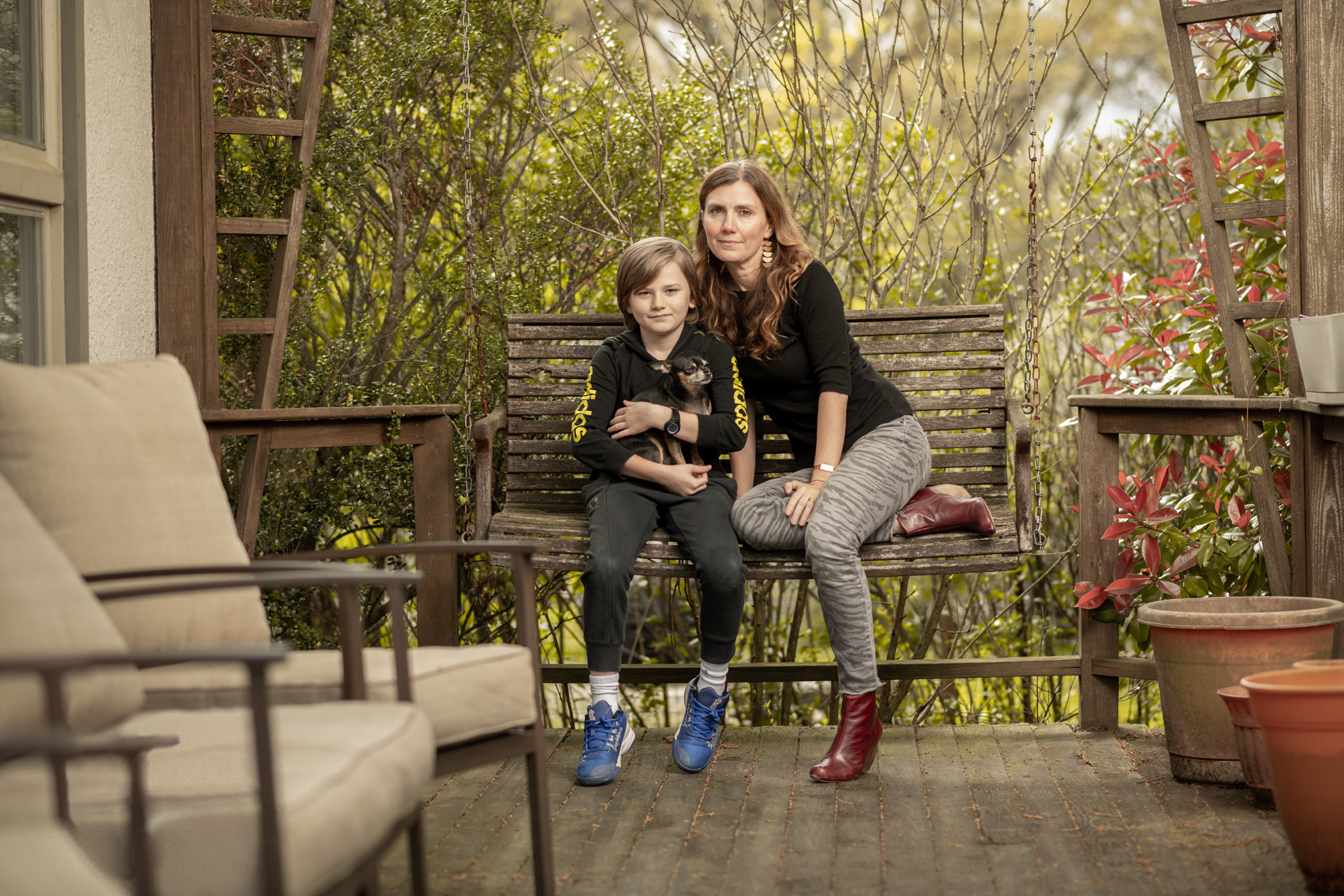 COVID-19 survivor Cara Ober and her son seated on a porch swing at her home