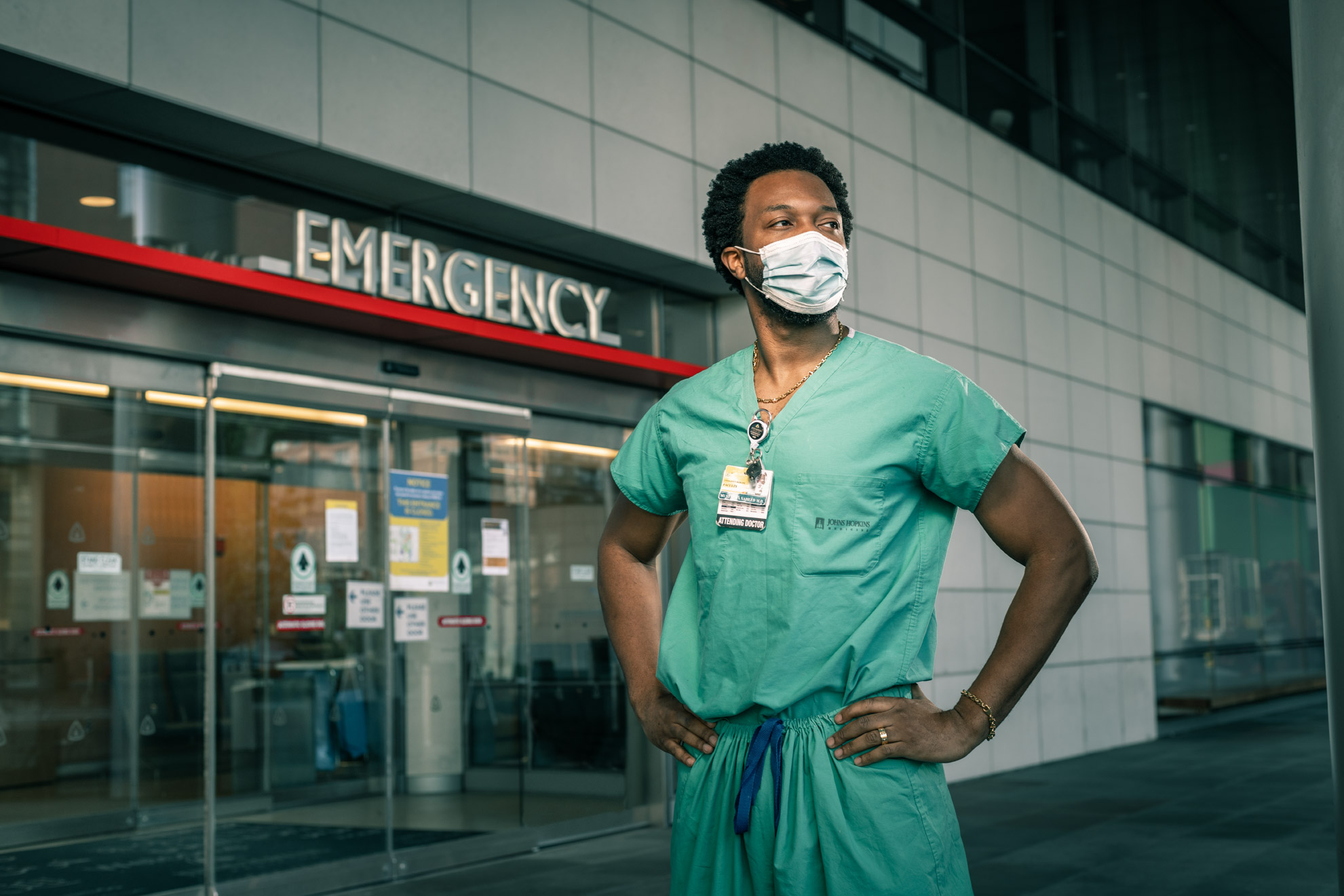 Dr. Mustapha Oladapo Saheed wearing scrubs and his COVID mask in front of the emergency entrance