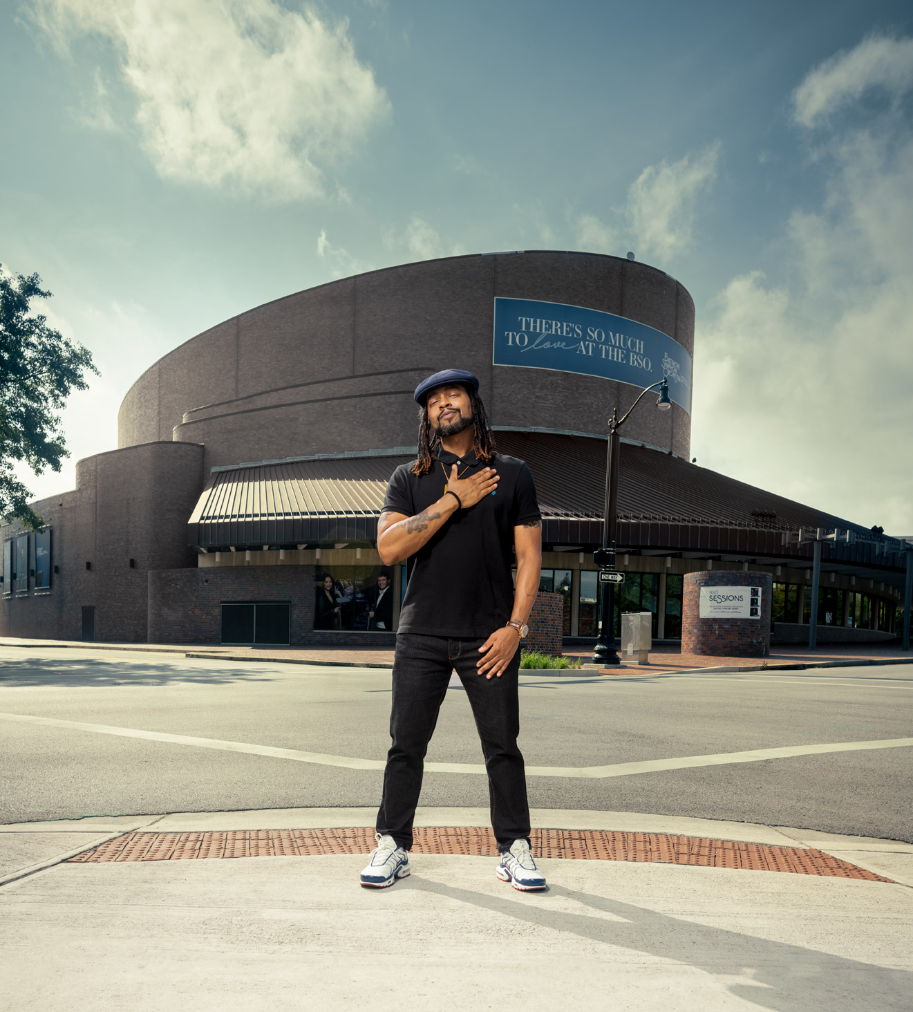 Wordsmith the rapper standing in front of the Meyerhoff Symphony Hall with his hand on his chest