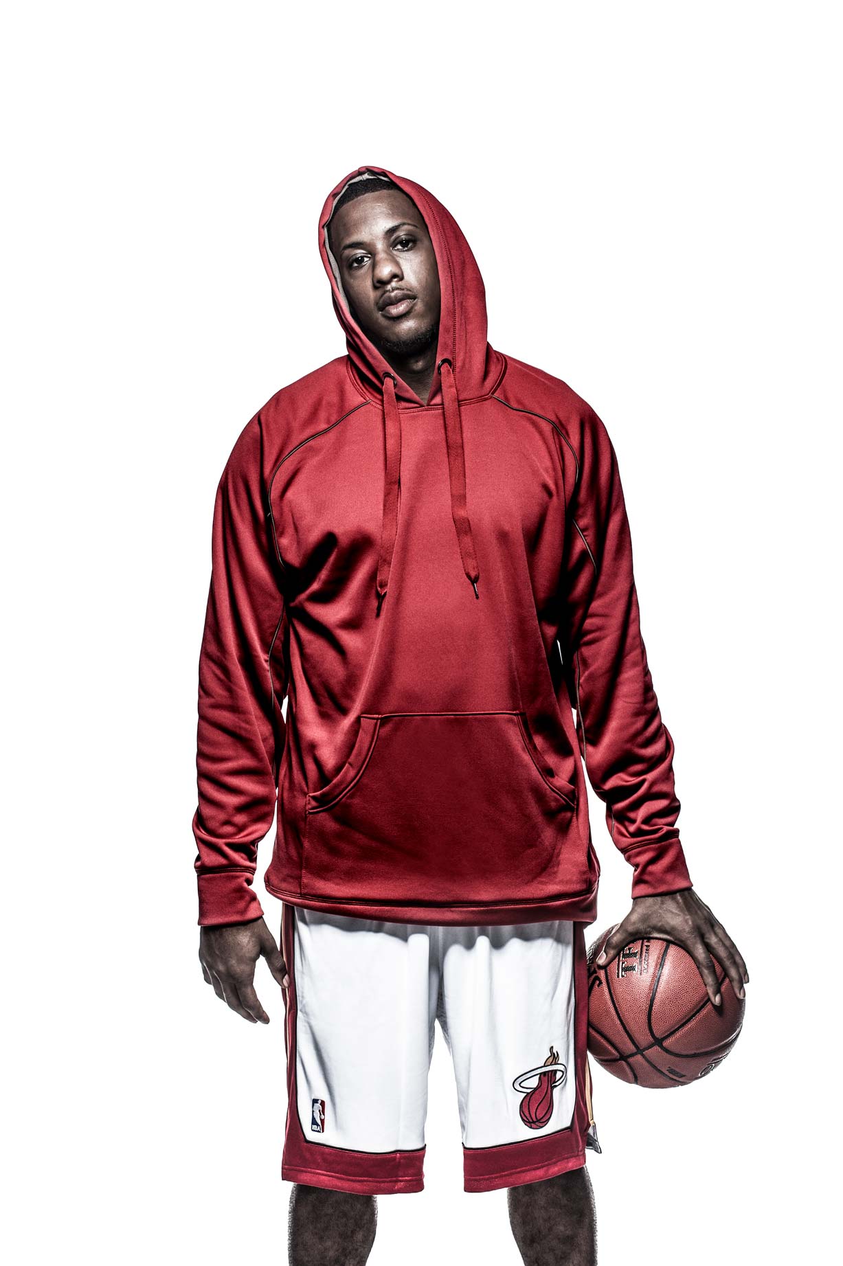 Mario Chalmers palming a basketball and wearing a red hooded sweatshirt on a white background